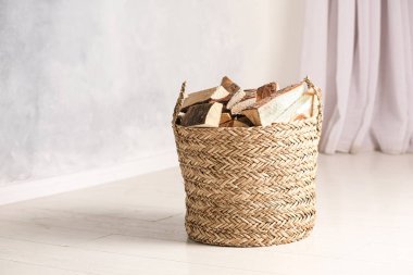 Beyaz zeminde kesilen odunlarla dolu bir sepet.