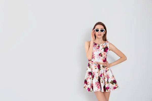Ung kvinna bär blommigt tryck klänning och snygga solglasögon på — Stockfoto