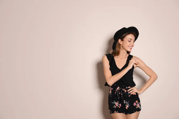 Młoda kobieta ubrana w kwiatowe szorty i stylowy kapelusz na beżu — Zdjęcie stockowe