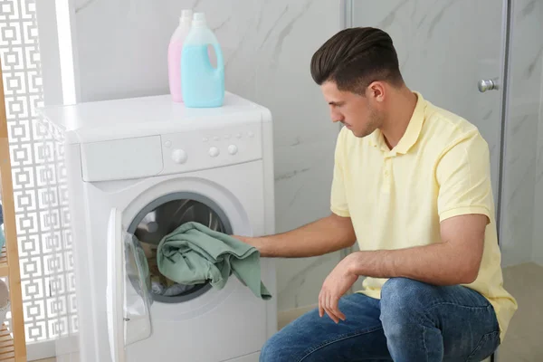 Mann steckt Kleidung in Waschmaschine im Badezimmer Wäscherei da — Stockfoto