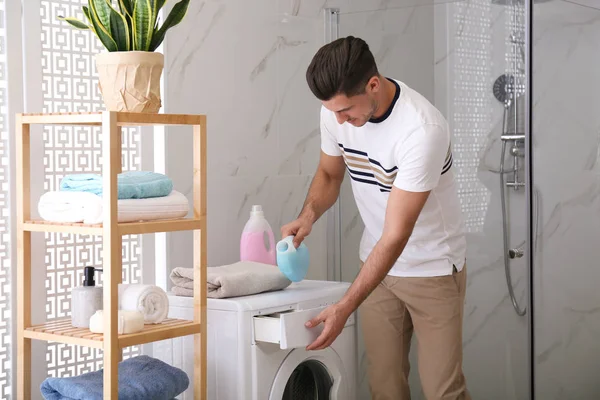 Man pouring detergent into washing machine drawer in bathroom. L — Stock Photo, Image