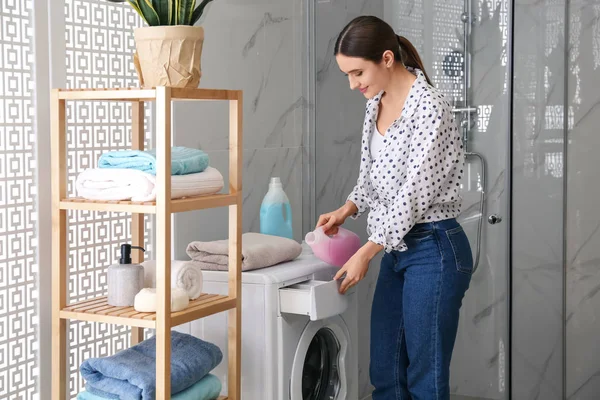 Mulher derramando detergente na gaveta da máquina de lavar roupa no banheiro . — Fotografia de Stock