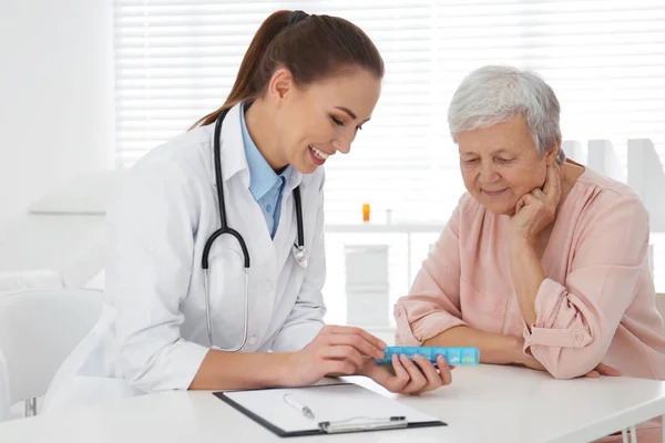 Médico dando pastillas al paciente mayor en el consultorio —  Fotos de Stock
