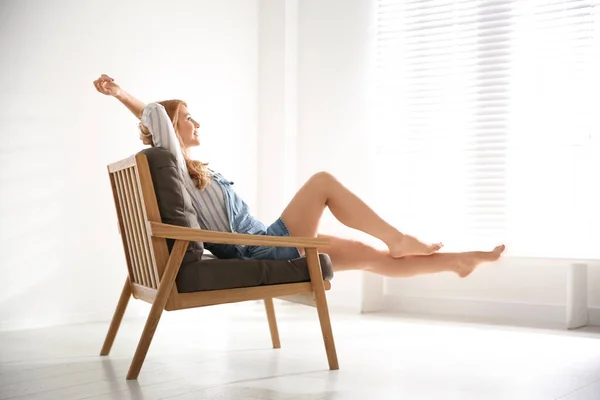 Молода жінка розслабляється в кріслі біля вікна вдома — стокове фото