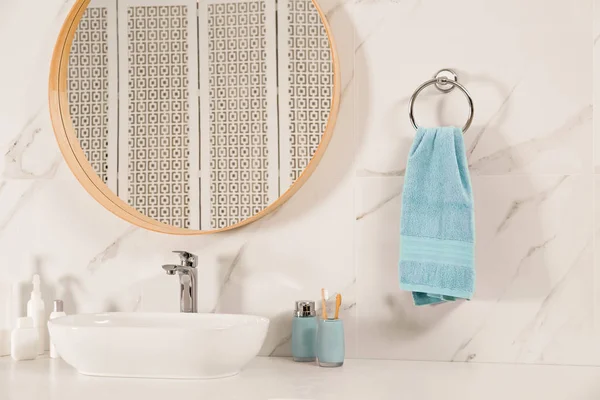 Banyo içinde ayna, tezgah ve duvarda yumuşak havlu var.