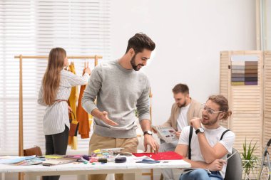 Moda tasarımcıları stüdyoda yeni kıyafetler yaratıyor.