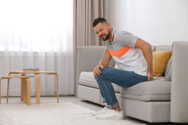 Evdeki koltukta hemoroitten muzdarip bir adam.