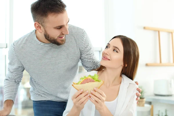 Ευτυχισμένο ζευγάρι με νόστιμο σάντουιτς στο σπίτι — Φωτογραφία Αρχείου