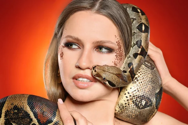 Vacker kvinna med boa constrictor på ljusa färgglada backgro — Stockfoto