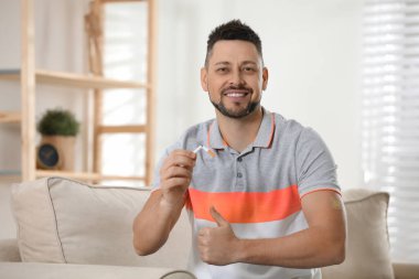 Evde nikotin bandı ve sigarası olan mutlu bir adam.