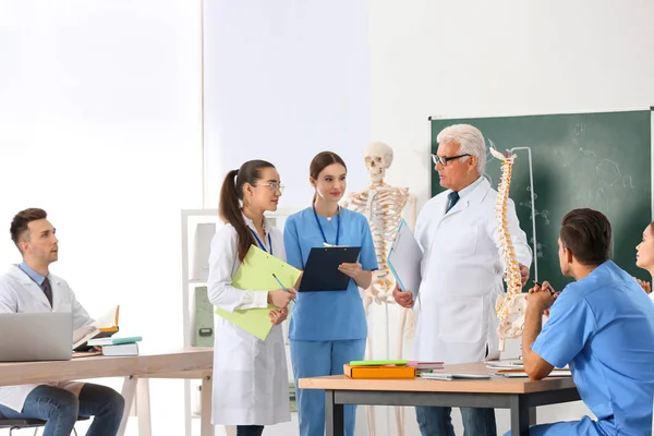 Medical students and professor studying human spine structure in classroom