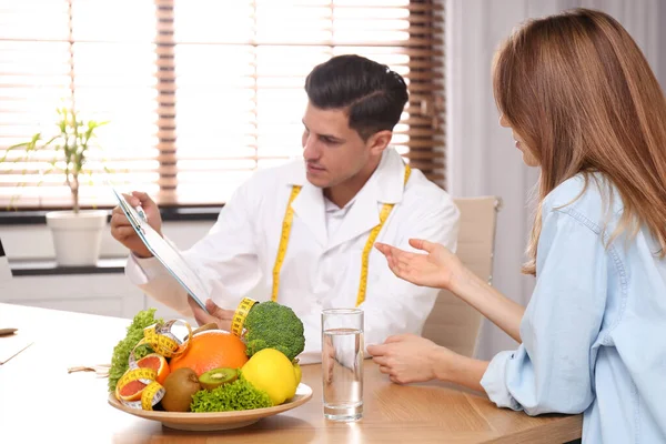 Nutritionist consulting patient at table in clinic — 스톡 사진