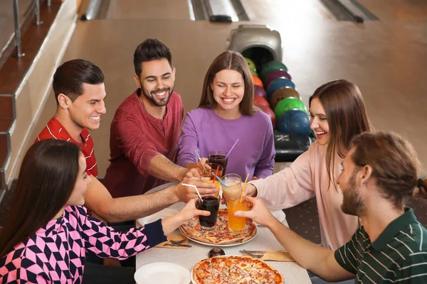 Groep vrienden met drankjes en pizza in bowlingclub — Stockfoto