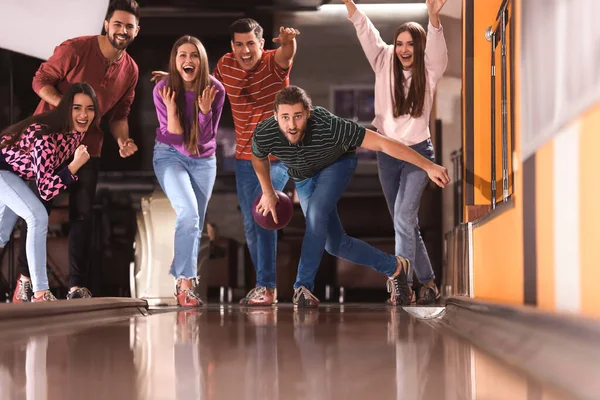 Ung man kastar boll och umgås med vänner i Bowlin — Stockfoto