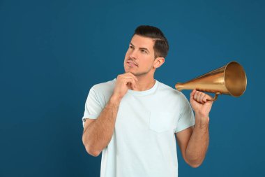 Mavi arka planda megafonu olan yakışıklı bir adam.