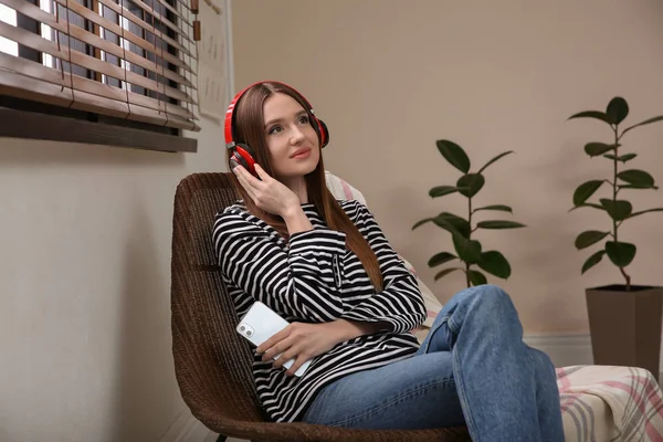 Mulher ouvindo audiolivro em cadeira em casa — Fotografia de Stock