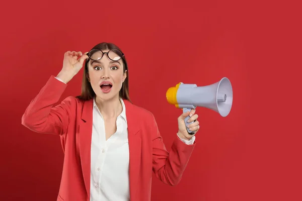 Mujer joven emocional con megáfono sobre fondo rojo — Foto de Stock