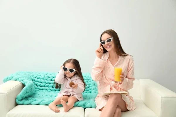 Madre e hija en albornoces sentadas en el sofá — Foto de Stock