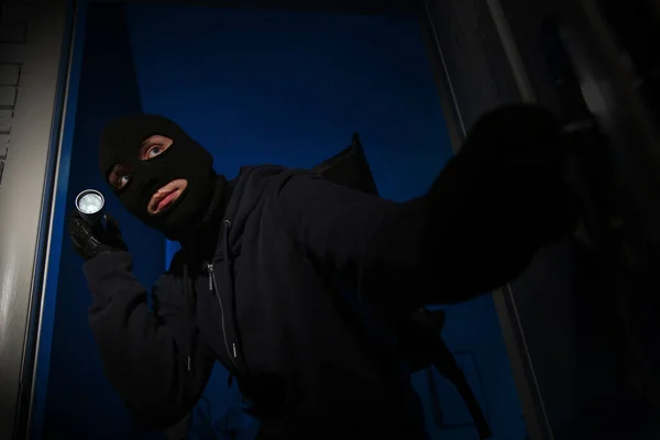 Ladrón con linterna irrumpiendo en casa por la noche — Foto de Stock