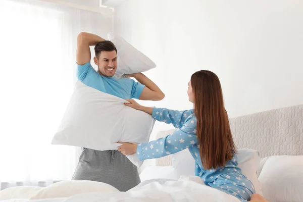 Szczęśliwa para mając walki na poduszki w sypialni — Zdjęcie stockowe