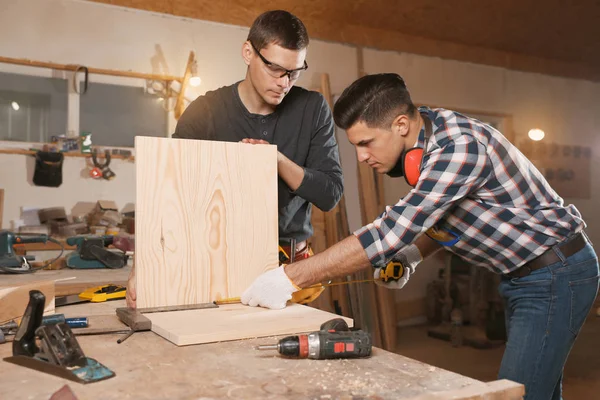 Carpinteros profesionales trabajando con tablas de madera en taller — Foto de Stock