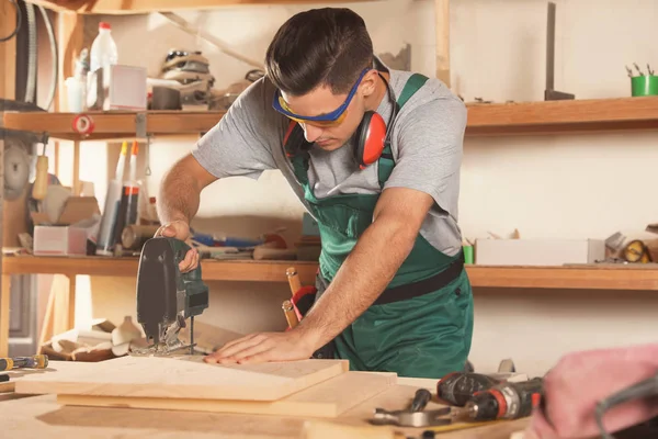 Professionele timmerman werkend met decoupeerzaag op werkbank — Stockfoto