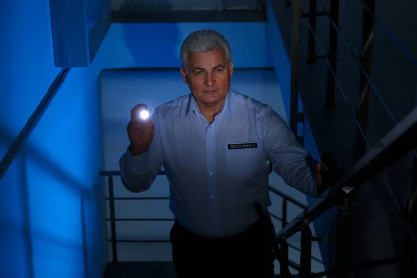 Profesjonalny ochroniarz z latarką na schodach w ciemnym ro — Zdjęcie stockowe