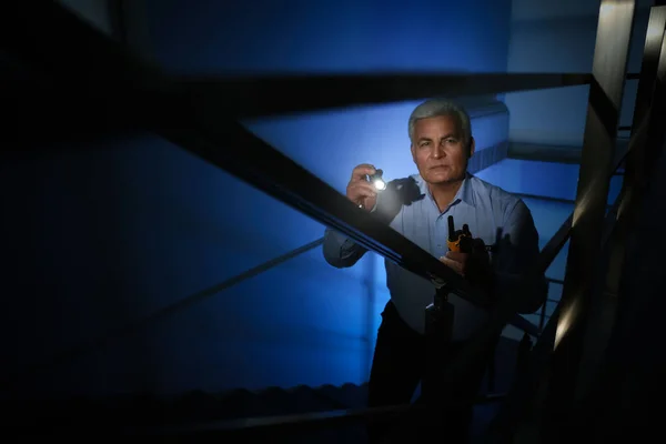 Professional security guard with flashlight on stairs in dark ro — Stock Photo, Image