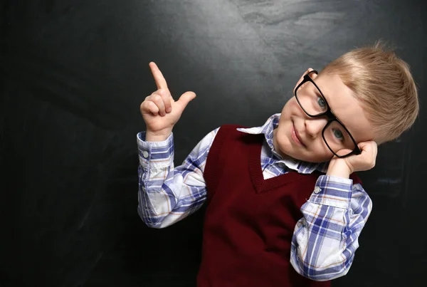 Gracioso niño pequeño con gafas cerca de pizarra. Primera vez a —  Fotos de Stock