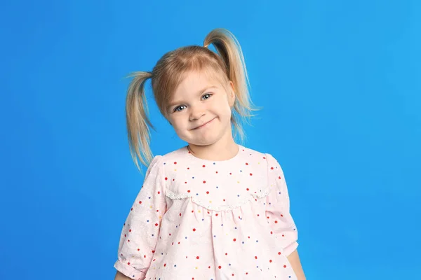 Portrét roztomilá holčička na modrém pozadí — Stock fotografie