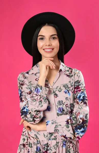 Jovem mulher vestindo vestido estampado floral e chapéu elegante em rosa b — Fotografia de Stock