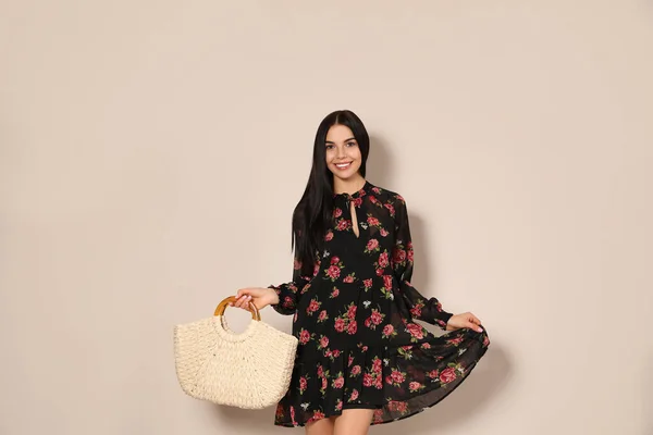 Ung kvinna bär blommig tryck klänning med sugrör väska på beige b — Stockfoto