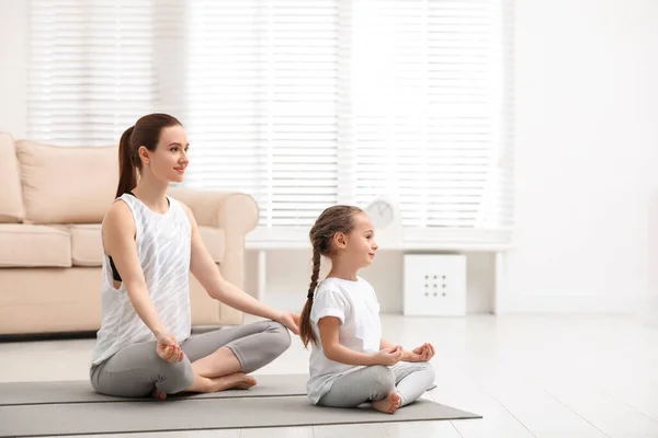 Молодая мама с дочкой практикуют йогу дома — стоковое фото