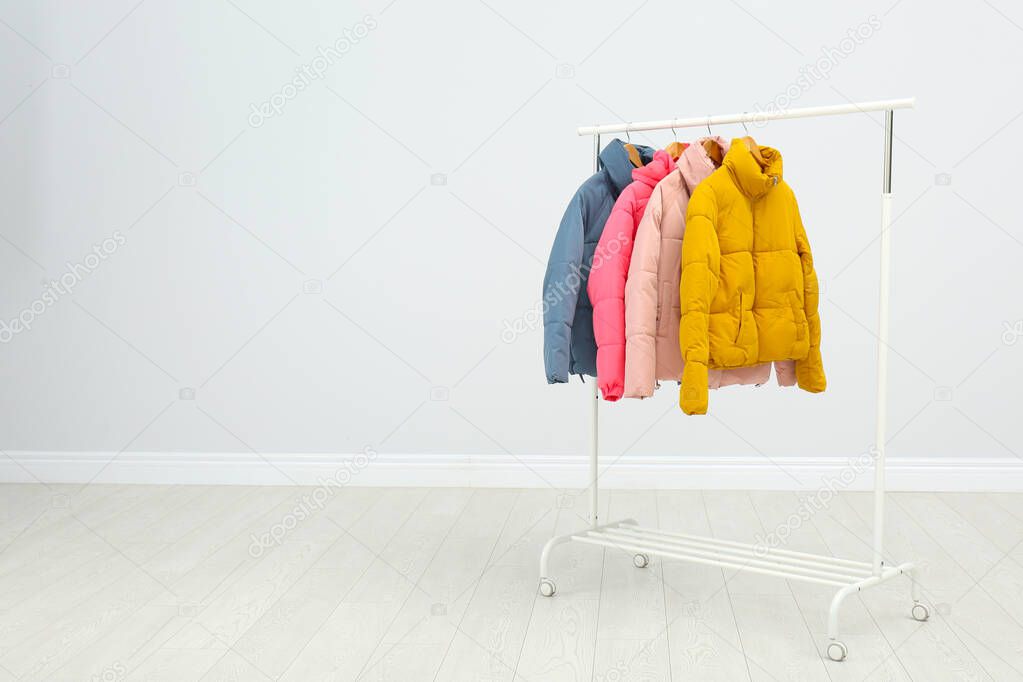 Rack with warm jackets in room. Space for text