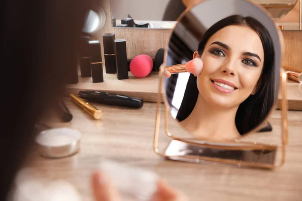 Piękna młoda kobieta stosując makijaż w pobliżu lustra w dressing ta — Zdjęcie stockowe