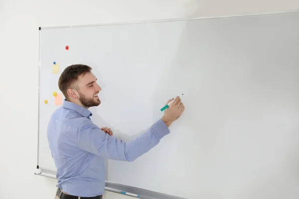 Retrato de un joven profesor escribiendo en pizarra blanca en el aula —  Fotos de Stock