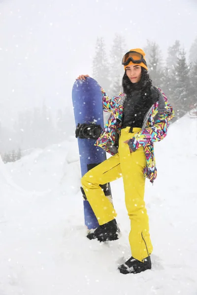 Mujer joven con snowboard usando ropa deportiva de invierno al aire libre —  Fotos de Stock