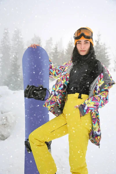 Молода жінка зі сноубордом в зимовому спортивному одязі на відкритому повітрі — стокове фото