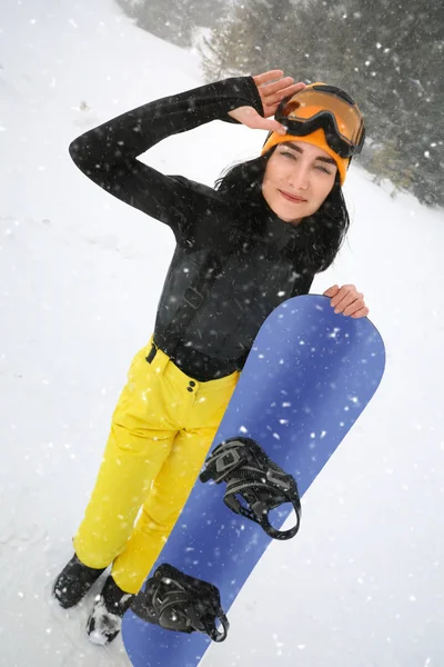 Mujer joven con snowboard usando ropa deportiva de invierno al aire libre —  Fotos de Stock