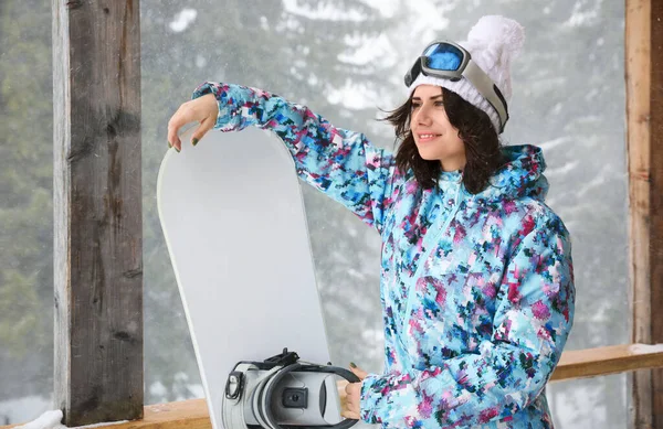 Mujer joven con snowboard usando ropa deportiva de invierno al aire libre — Foto de Stock