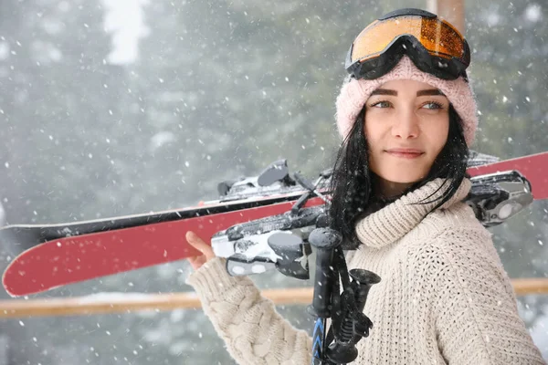 Jeune femme avec des skis portant des vêtements de sport d'hiver et des lunettes o — Photo