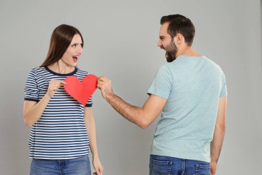 Açık gri arka planda kağıt kalp yırtan bir çift. İlişki sorunları
