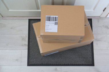 Kapının yanındaki halıda karton kutular, üst manzara. Paket teslimat servisi