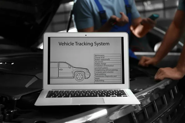 Laptop with vehicle tracking system and blurred mechanics on bac — 스톡 사진