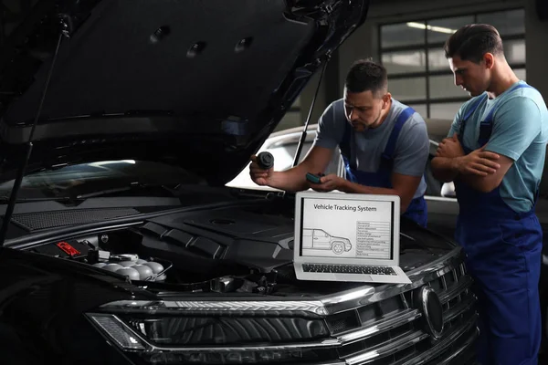 Laptop mit Fahrzeug-Tracking-System und unscharfe Mechanik auf bac — Stockfoto
