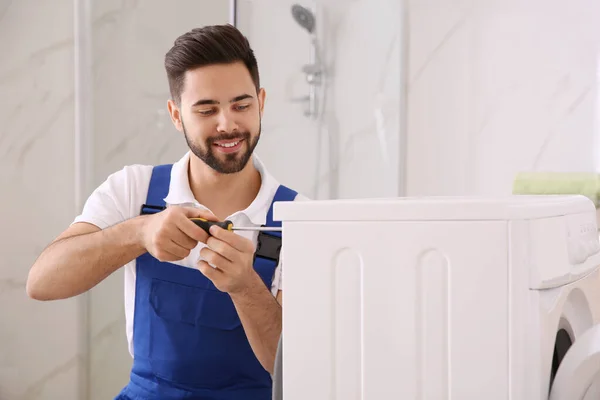 Professionell rörmokare reparera tvättmaskin i badrummet — Stockfoto