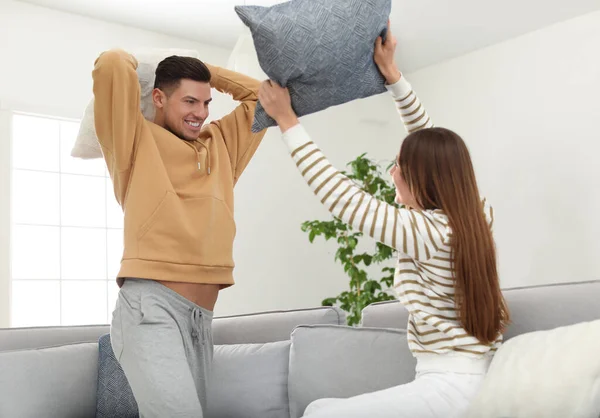 Feliz pareja teniendo pelea de almohadas en la sala de estar — Foto de Stock