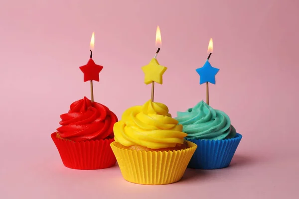 Lahodné narozeninové dortíky s hořícími svíčkami na růžovém backgro — Stock fotografie