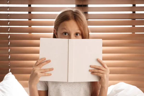Érzelmes tizenéves lány könyv az ágyon ablak mellett — Stock Fotó