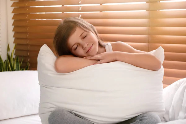 Χαριτωμένο κορίτσι preteen με μεγάλο μαξιλάρι στο κρεβάτι κοντά στο παράθυρο — Φωτογραφία Αρχείου